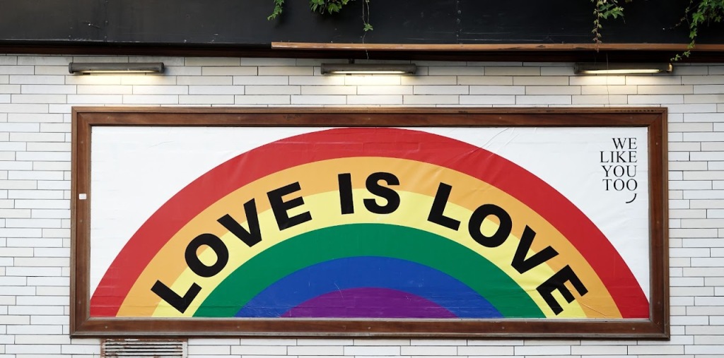 A rainbow with the text "Love is Love". In the right corner of the picture, there is text that says "We like you too".